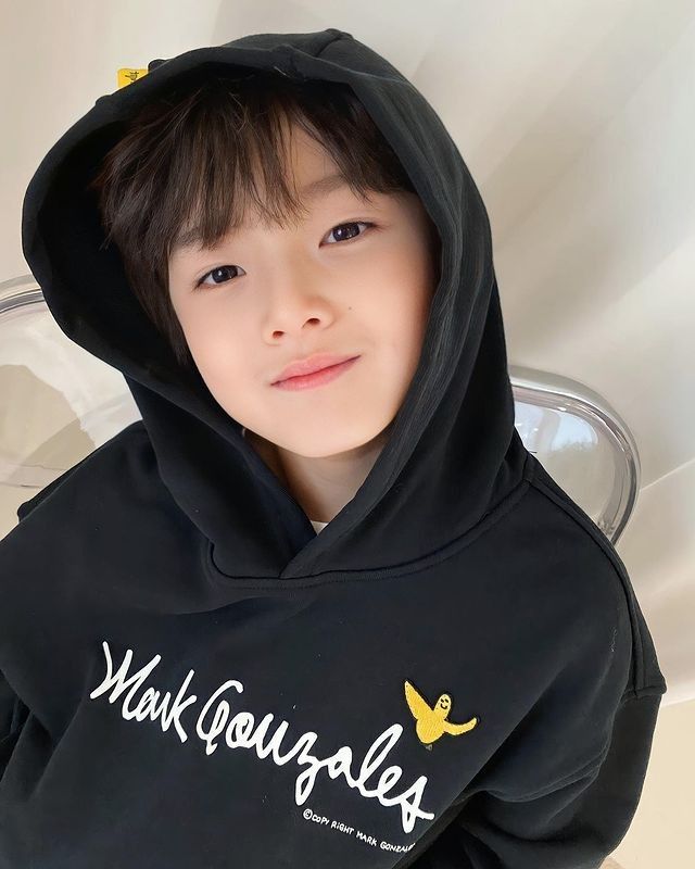 a young boy wearing a black hoodie with the words make yourself smile on it