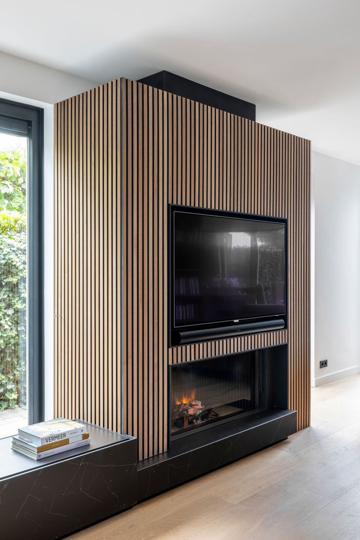 a living room with a large television mounted on the wall next to a fire place