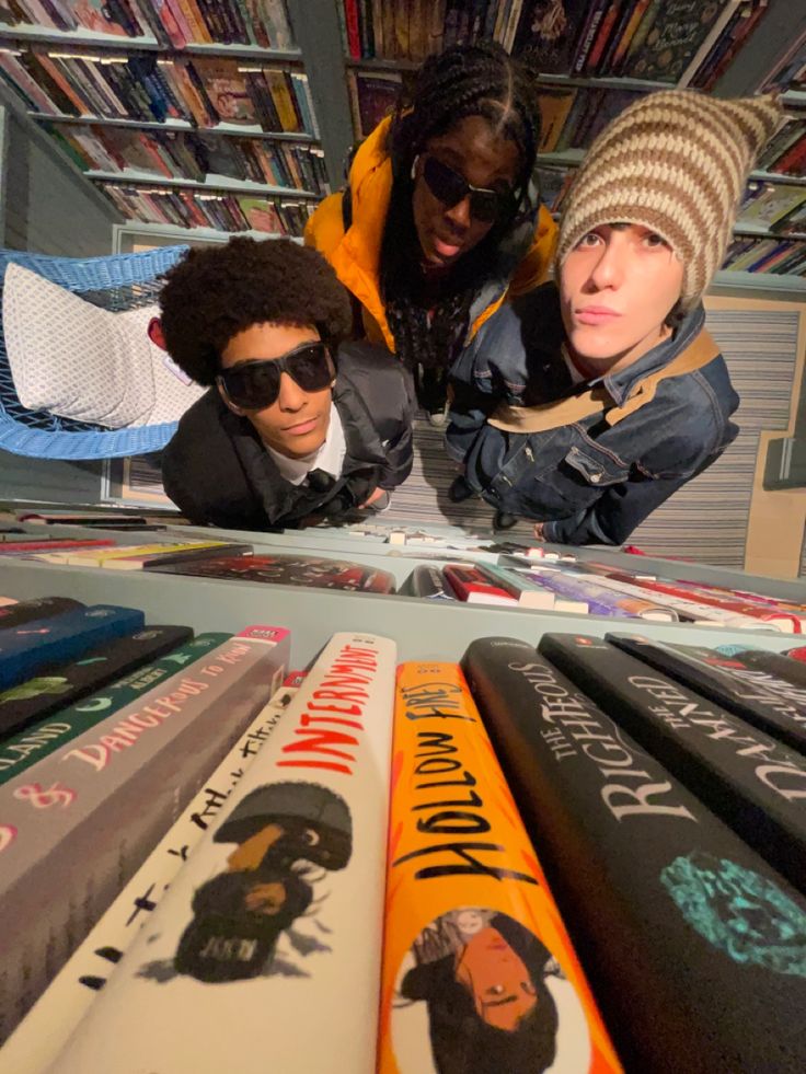 three people are looking at books in a book store while one person is taking a selfie