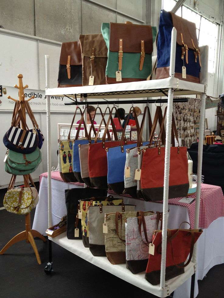 several purses and bags are on display in a room with white tablescloths