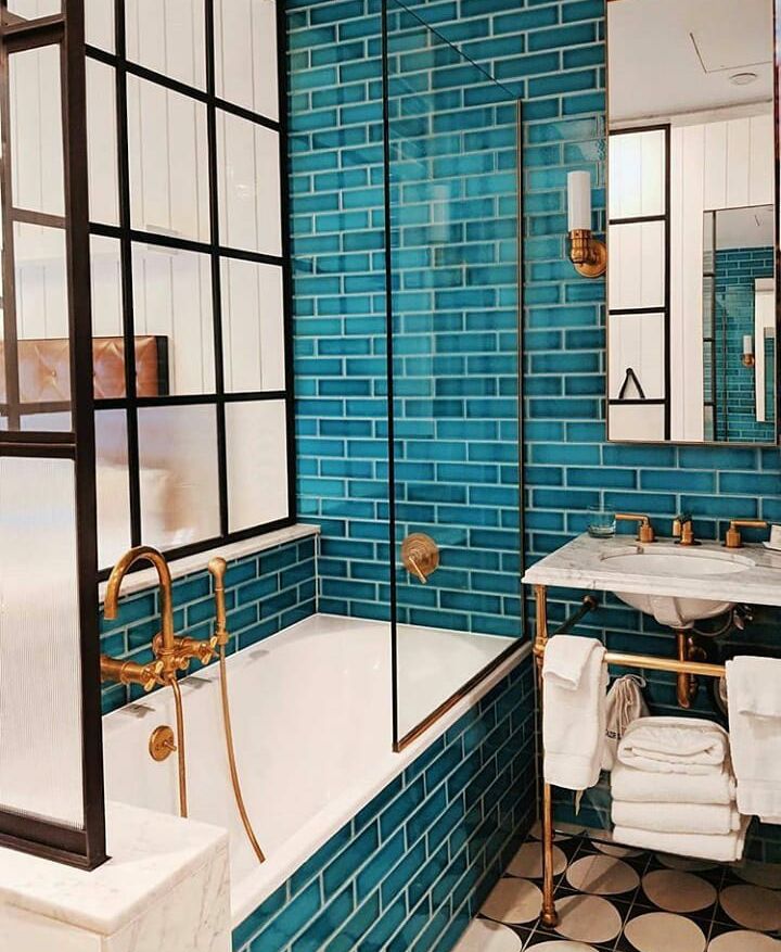 a bathroom with blue tiles and black and white tile on the floor, along with a bathtub