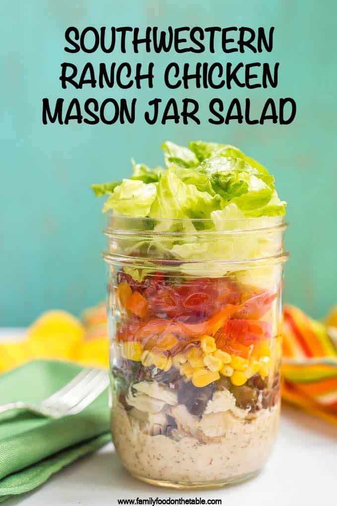 a salad in a jar with lettuce, tomatoes, corn and dressing on top