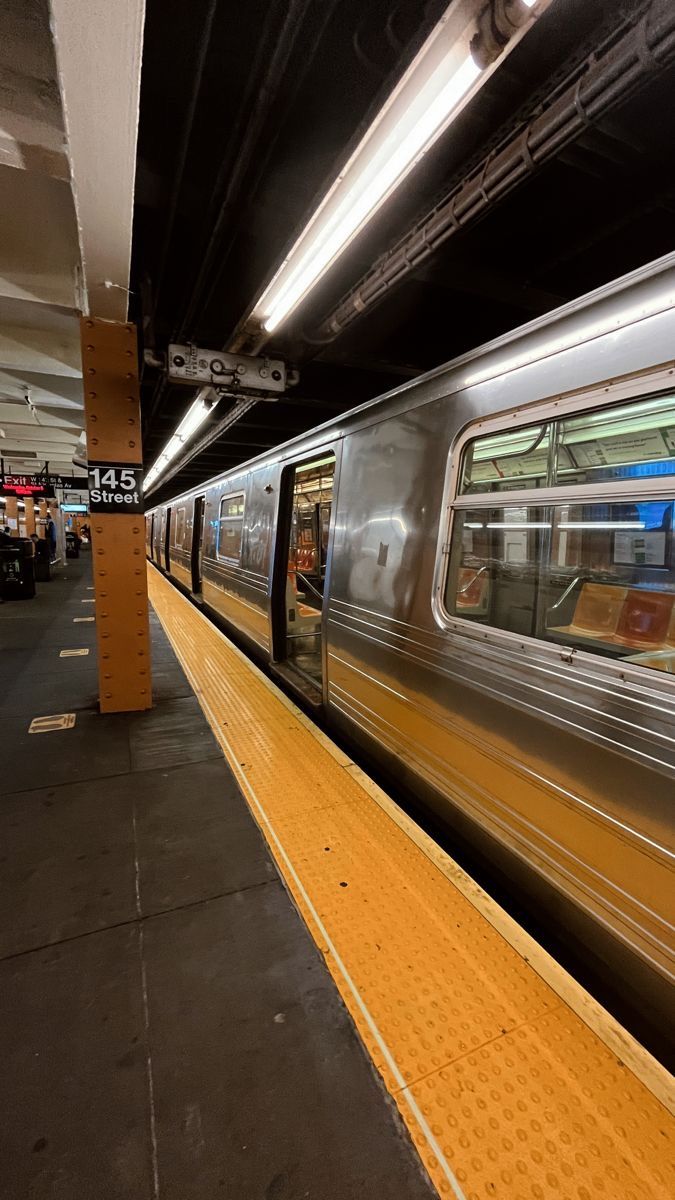 a silver train traveling down tracks next to a loading platform