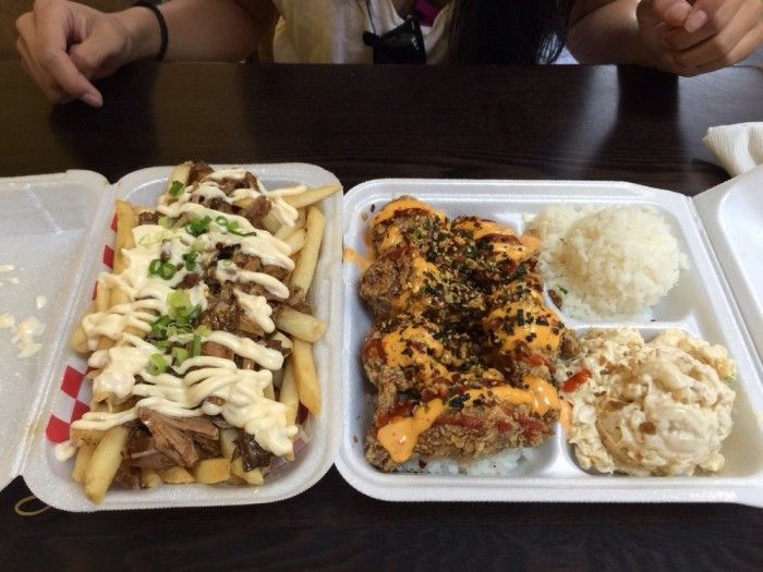 two take out trays filled with different types of food on top of a table