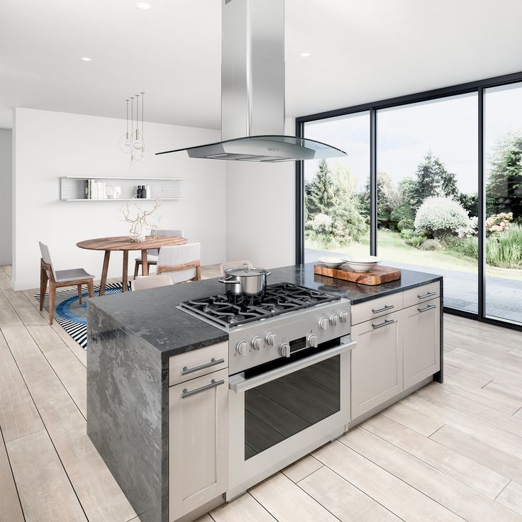 a kitchen with an oven, stove and dining table in front of large glass doors