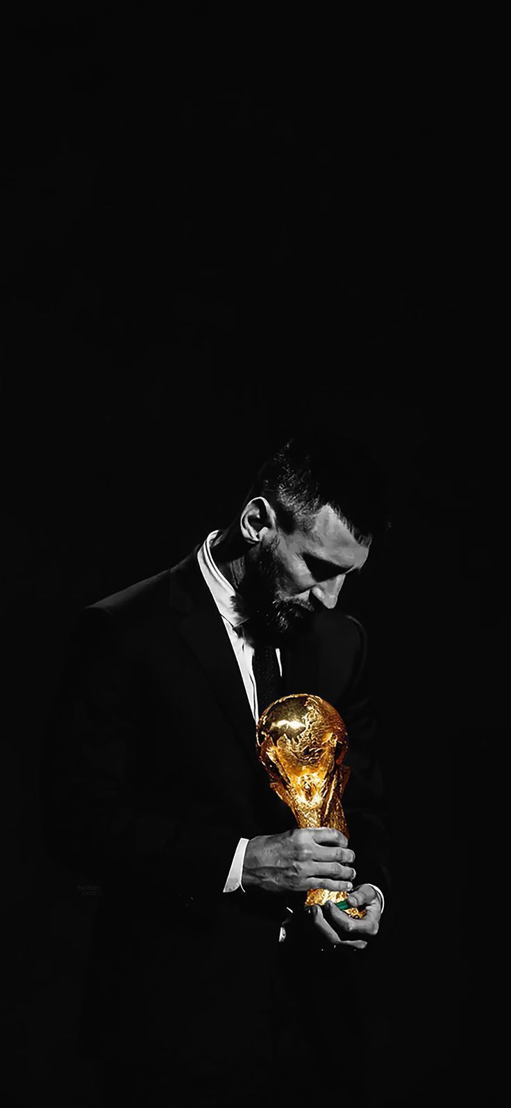 a man in a suit holding a golden trophy and looking down at his face with one hand