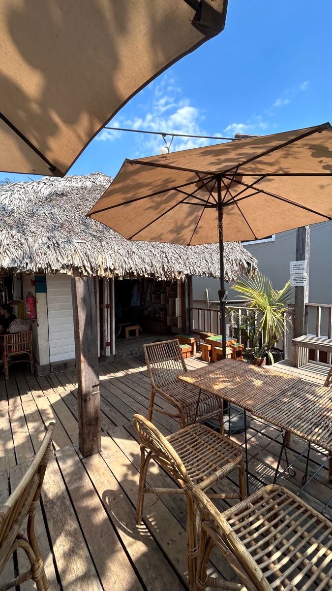 an outdoor dining area with tables and umbrellas on wooden decking next to building