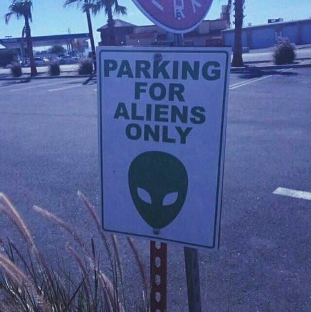 a parking sign with an alien face on it