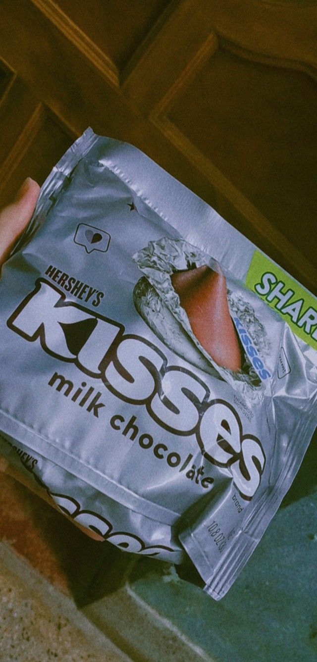 a hand holding a bag of kisses milk chocolate