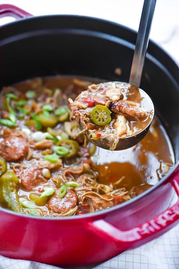 a ladle full of soup with meat and vegetables