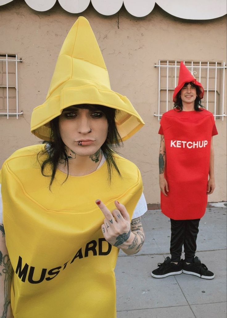 two people dressed up in costumes standing on the sidewalk and one is wearing a ketchup shirt