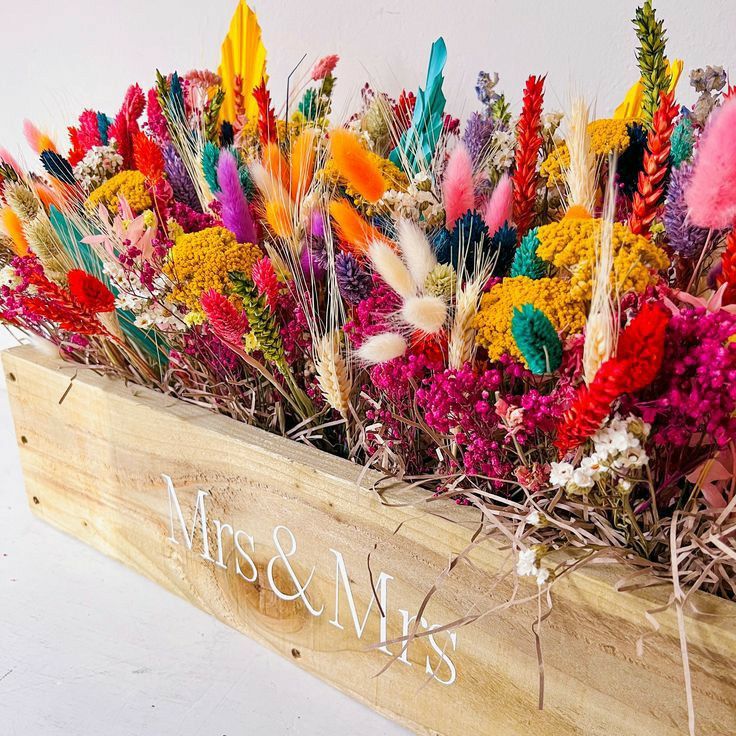 a wooden box filled with lots of colorful flowers next to a sign that says mrs and mrs