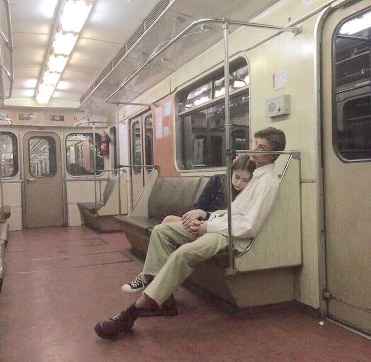 two people are sitting on the subway car