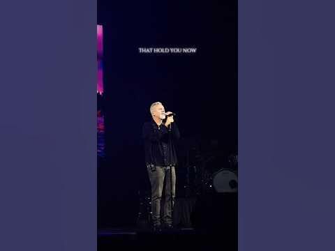 a man standing on top of a stage holding a microphone in front of his face