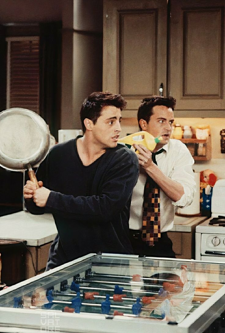 two men standing in a kitchen with one holding a magnifying glass and the other looking at something