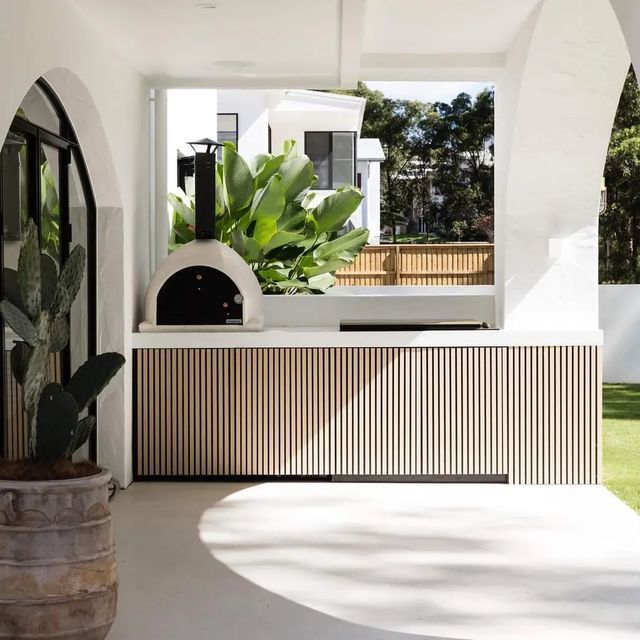 an outdoor kitchen with a pizza oven and potted plants