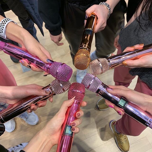 a group of people holding microphones in the middle of a circle with their hands together