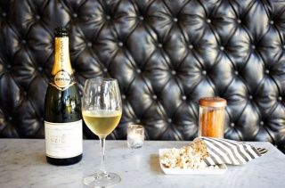 two glasses of wine and a bottle on a table in front of a leather wall