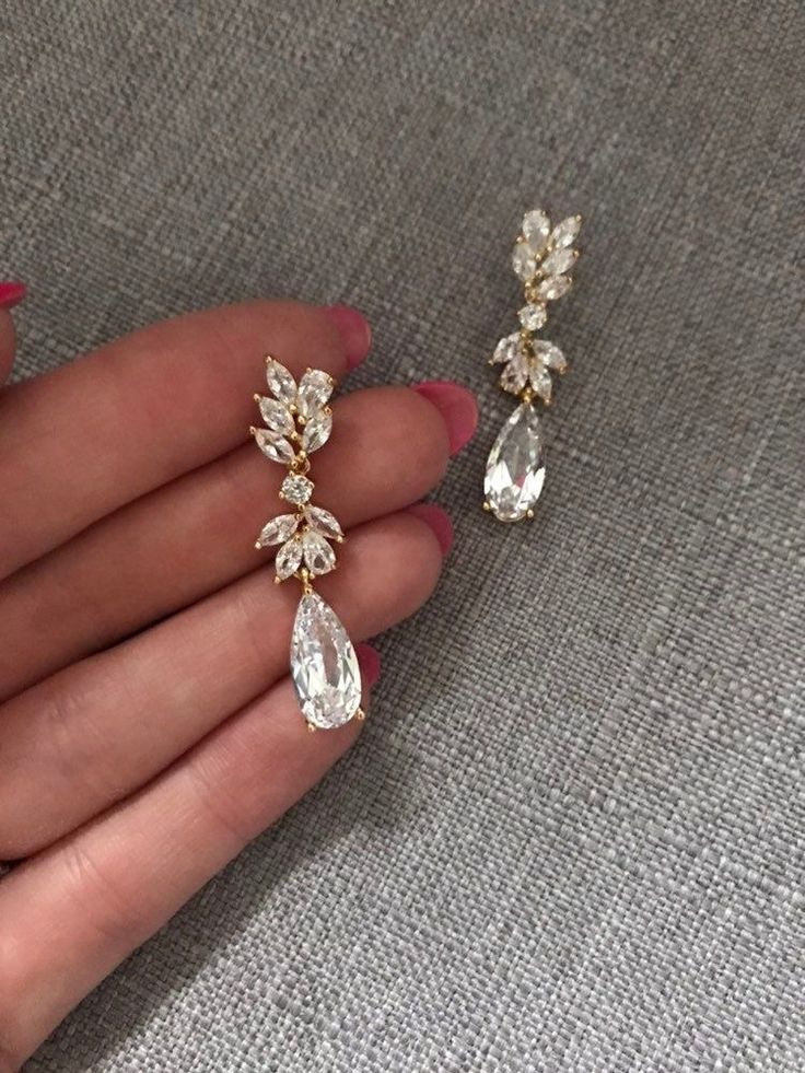 a woman's hand holding two pairs of earrings on her left and right hand