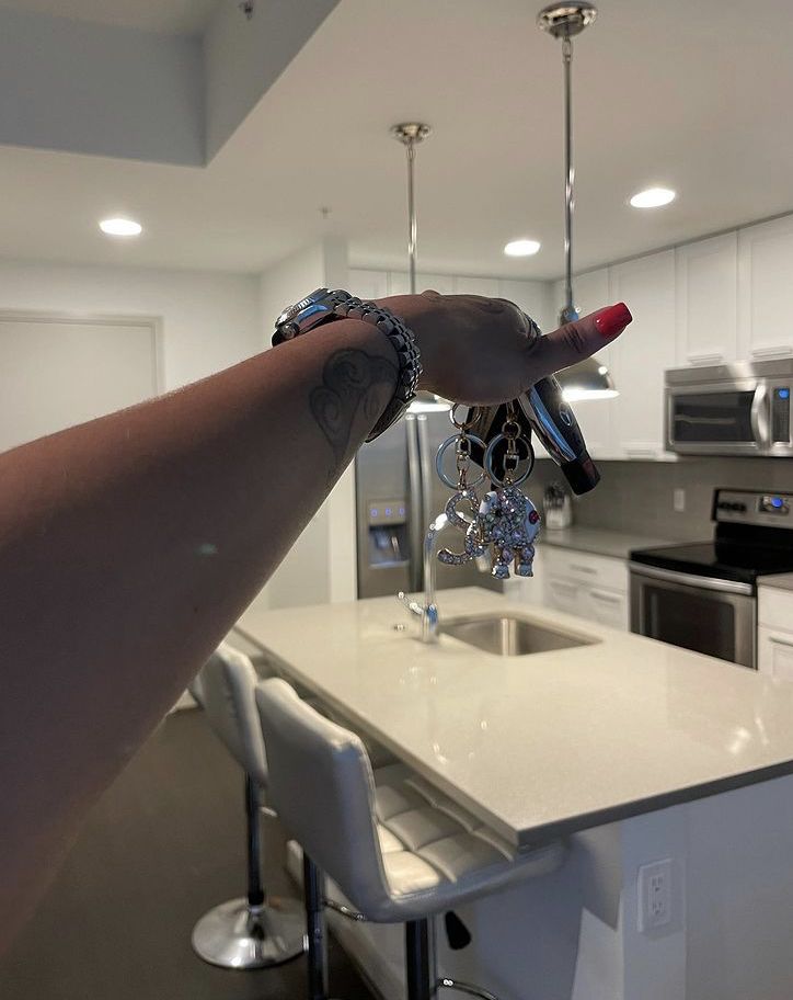 a woman's arm with bracelets hanging from the ceiling in a kitchen next to an island