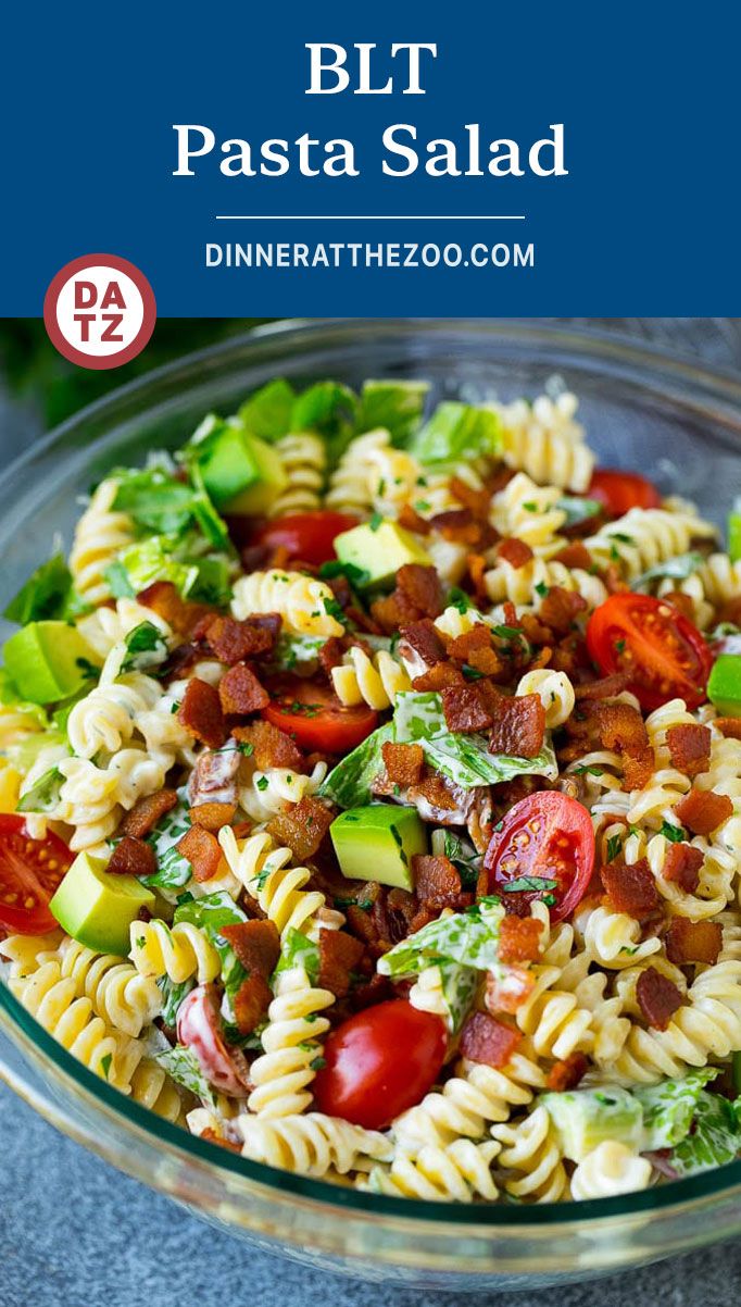 a pasta salad with bacon, tomatoes and lettuce in a glass bowl