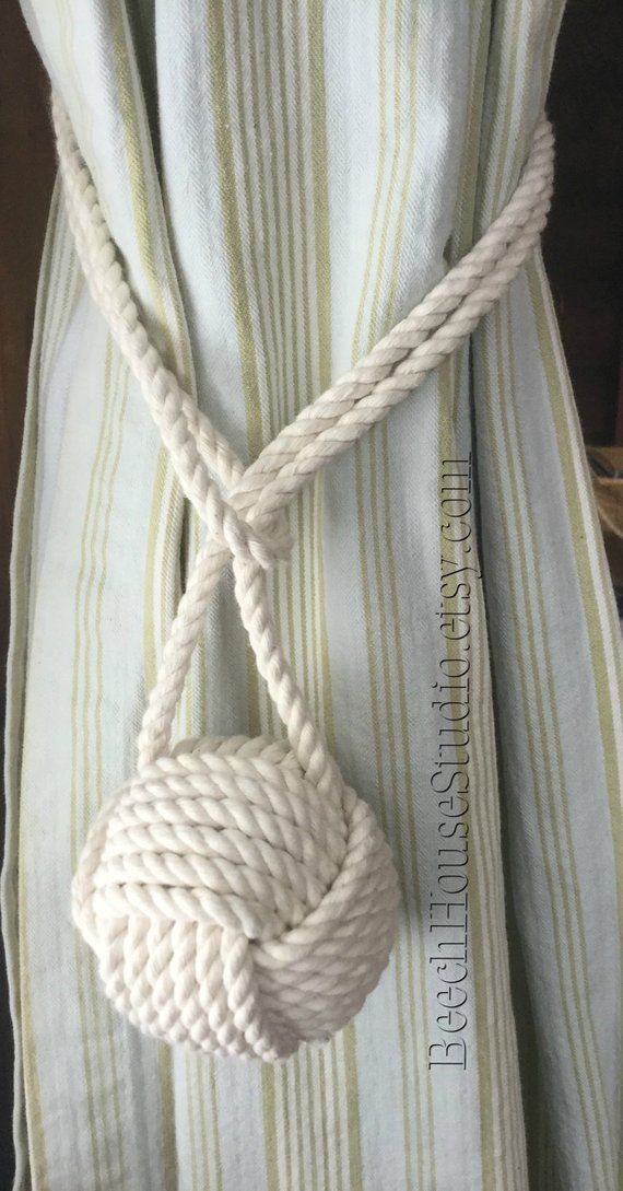 a white rope tied to the side of a striped curtain with a knot on it