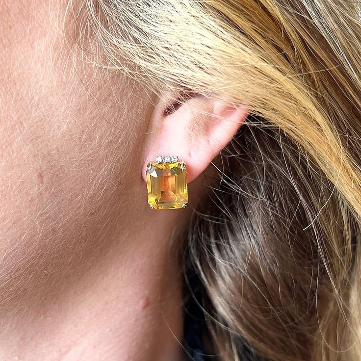 Mid-Century Citrine Stud Earrings in 14k Yellow Gold From home design to one of a kind jewelry, the Mid-Century era brought a movement of elegance and geometry together in dazzling ways. These Mid-Century citrine stud earrings feature two (2) 7.12 carat emerald cut citrines and diamond accents in 14 karat yellow gold. The citrines feature a marigold-orange hue. Six (6) white accent diamonds decorate the tops of the impressive citrine gemstones. Finished in polished 14 karat yellow gold. Radiant Timeless Citrine Jewelry For Formal Occasions, Formal Yellow Earrings With 17 Jewels, Yellow Earrings With 17 Jewels For Formal Occasions, Evening Gemstone Earrings In Fine Jewelry Style, Fine Jewelry Gemstone Earrings For Evening, Elegant Citrine Jewelry With Prong Setting, Yellow Gold Gemstone Earrings For Party, Yellow Gold Prong Setting Earrings For Party, Elegant Formal Citrine Earrings