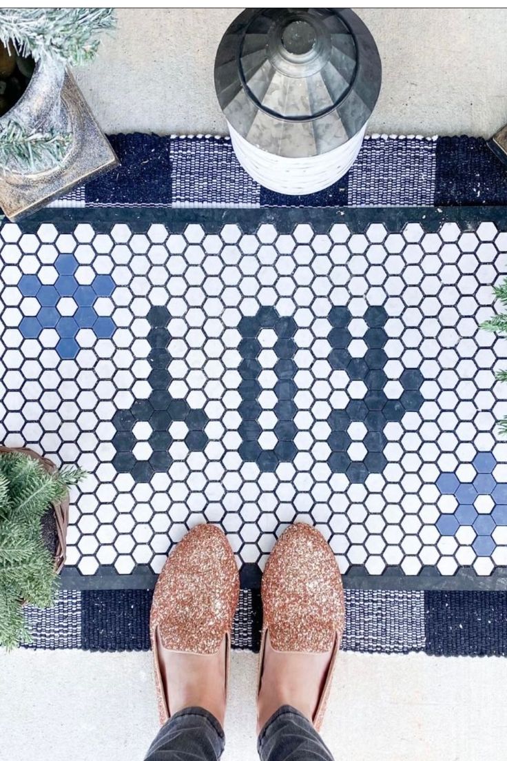 a person standing in front of a door mat with the word budi on it