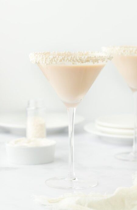 two martini glasses filled with white wine and garnished with sugar on the rim