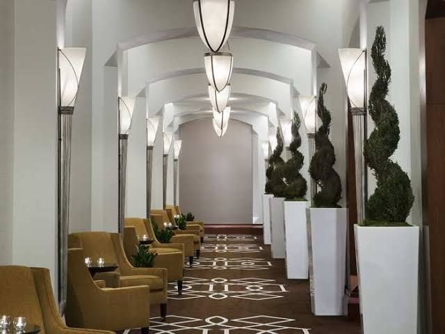 the hallway is lined with chairs and potted plants on either side of the tables