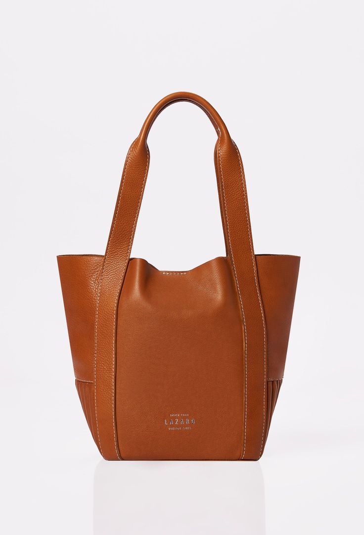 Front of a Tan Leather Mini Bucket Bag Ushuaia with Lazaro logo and contrast stitching highlights. Satchel Bags With Leather Handles For Everyday, Timeless Pouch Shoulder Bag With Dust Bag, Timeless Satchel With Leather Handles For Daily Use, Everyday Top Handle Leather Bag, Functional Everyday Satchel With Leather Lining, Everyday Functional Satchel With Leather Lining, Daily Top Handle Bag With Leather Handles, Timeless Travel Shoulder Bag With Dust Bag, Timeless Cognac Bag With Leather Handles