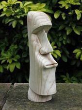 a white sculpture sitting on top of a wooden table next to some bushes and trees