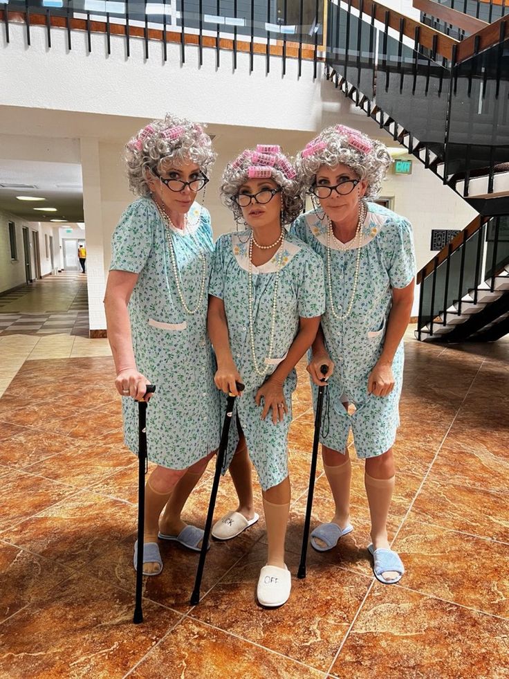 three older women dressed in blue dresses and holding canes standing next to each other