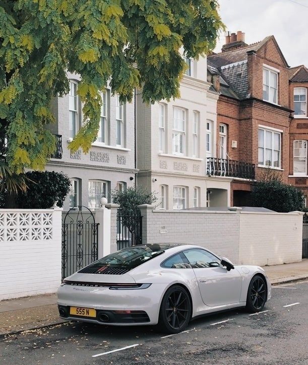 a white sports car parked on the side of the road in front of some houses