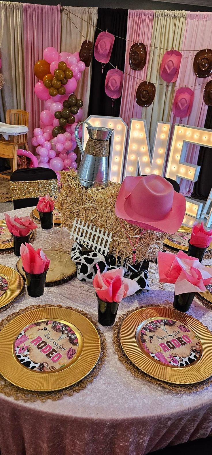 a table topped with plates and cups filled with pink flowers next to a sign that says one