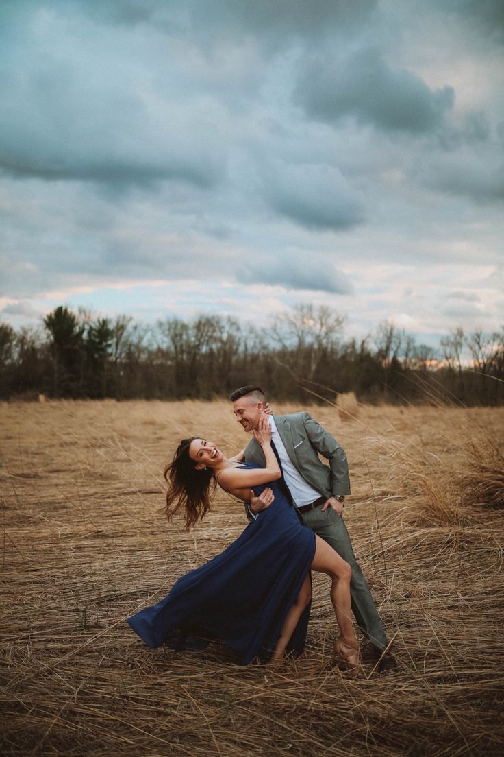 a man and woman are dancing in the middle of an open field with tall grass