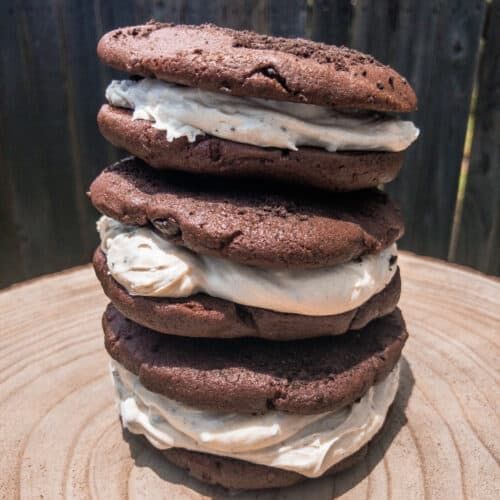 a stack of cookies sitting on top of a wooden table covered in ice cream and chocolate