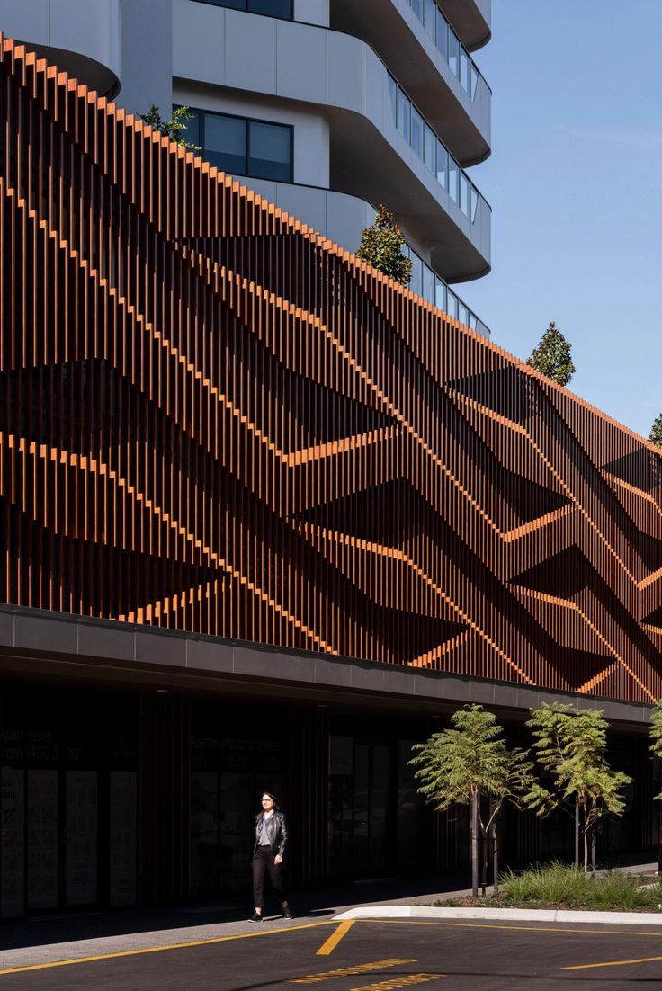 a person walking down the street in front of a building with wooden slats on it