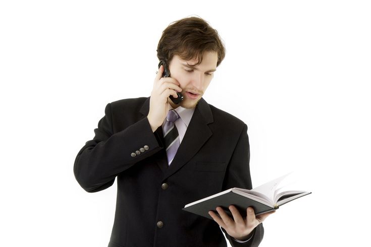 a man in a suit is talking on the phone and reading a book