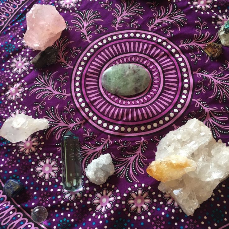 some rocks and crystals are on a purple table cloth with a circular design around them