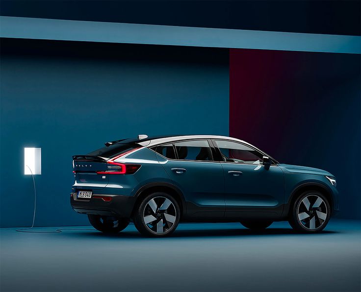 the new volvo suv is parked in front of a blue wall with an electric charger