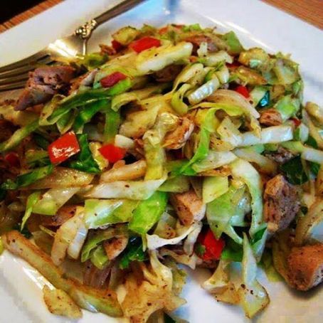 a white plate topped with meat and veggies next to a fork on a wooden table