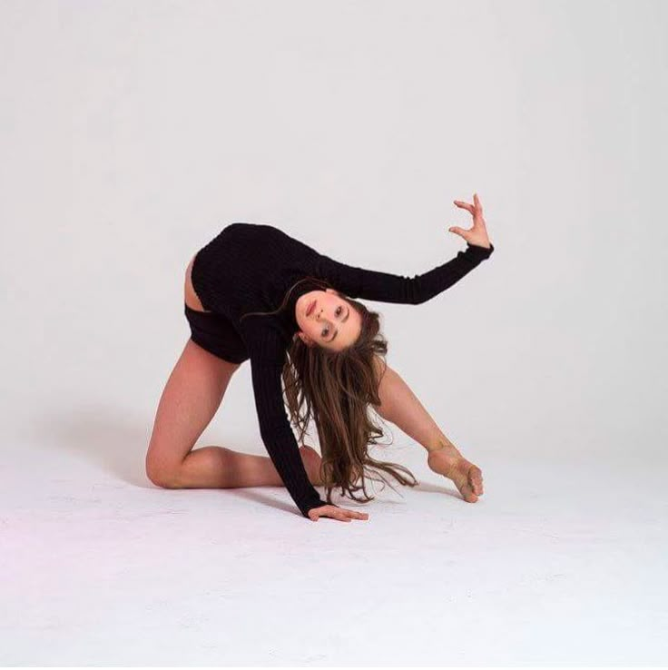 a woman in black is posing on the floor with her hands up and legs spread out