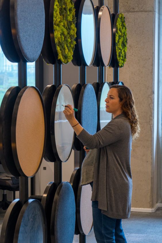 a woman standing in front of a display of round mirrors with plants growing on them