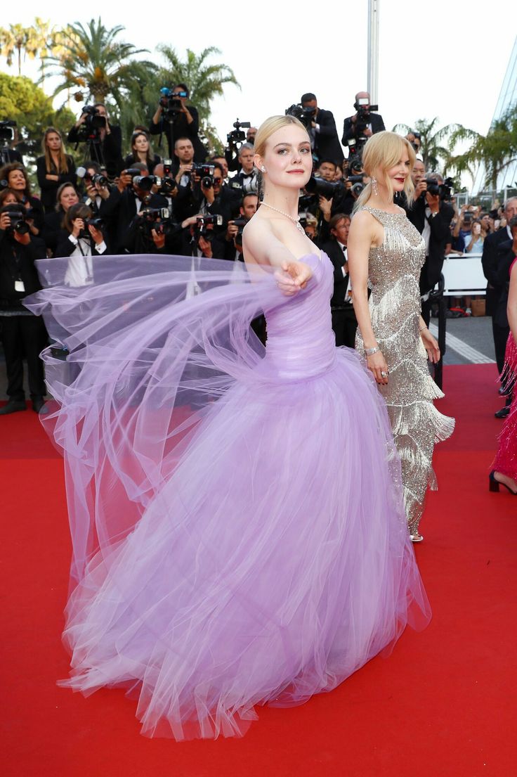 two women standing on a red carpet next to each other with cameras in the background