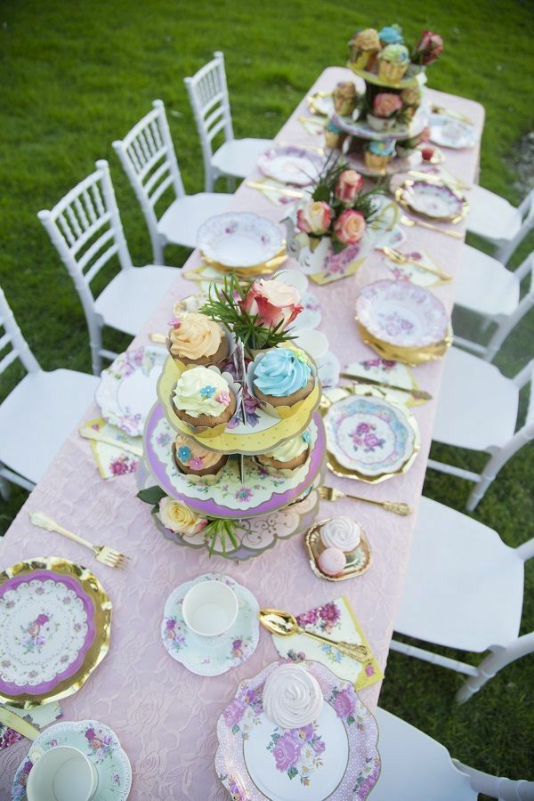 a long table with plates, cups and saucers on it is set up for a tea party