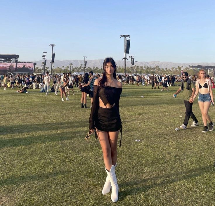 a woman standing on top of a lush green field next to a crowd of people