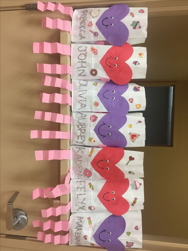 some pink and purple paper with hearts on them hanging from the wall in front of a door