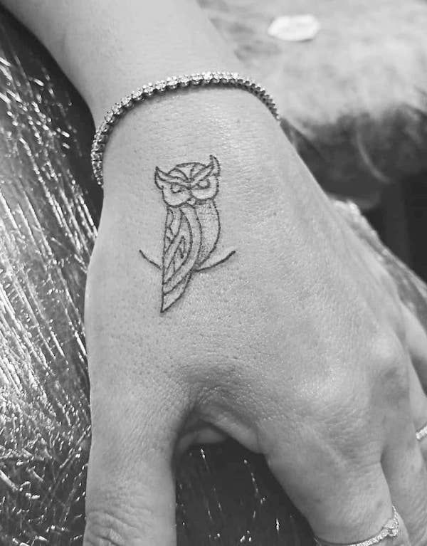 a small owl tattoo on the left hand is shown in this black and white photo