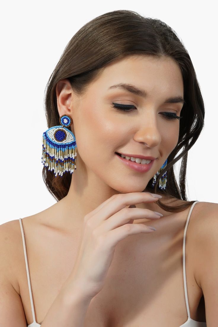 Evil Eye Beaded Earrings Hand-beaded Crafted in Beautiful Colors of Blue, Gold and White All the glamour and magic of a Grecian night wrapped up in the beautiful waves of colour this earring adds to your outfit. The vivid colours are complemented by a playful beaded fringe tassel, adding that perfect touch of glitz!Make heads turn with your contemporary style as you add some pizazz to your outfit with this stunning eye candy for your ears. An absolutely stunning pop of colour, this uniquely craf Summer Party Beaded Drop Earrings, Blue Beaded Drop Earrings For Festival, Eye-catching Dangle Earrings For Party, Summer Chandelier Earrings With Round Beads, Party Teardrop Beaded Earrings With Dangling Beads, Summer Party Beaded Chandelier Earrings, Summer Blue Jewelry With Dangling Beads, Blue Beaded Tassel Drop Earrings, Blue Evil Eye Dangle Earrings